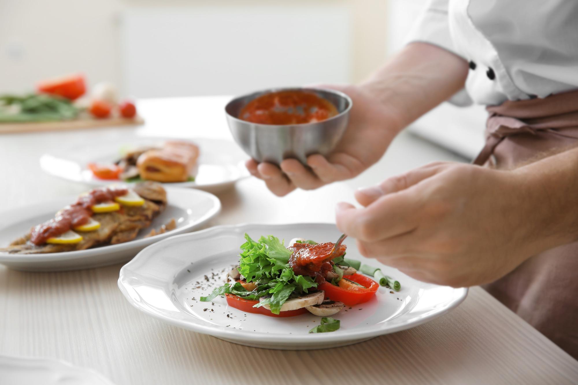 Chef demonstrating plating technique on a wooden table